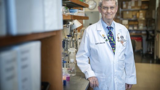A man in a white coat standing in a lab