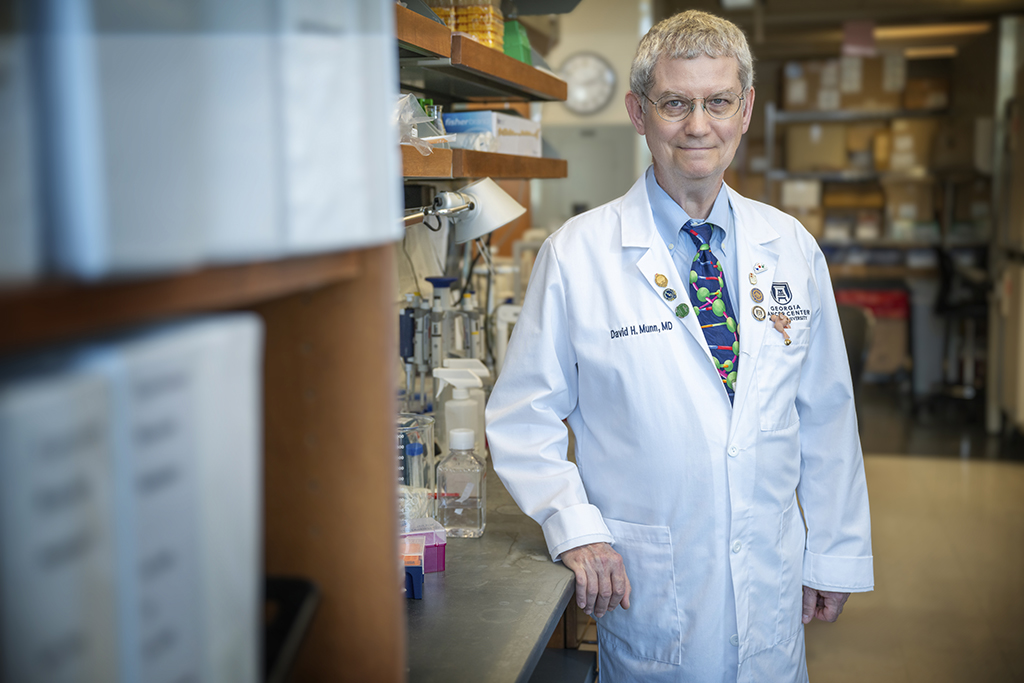 A man in a white coat standing in a lab