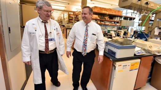Two men walking down the hallway between research labs.