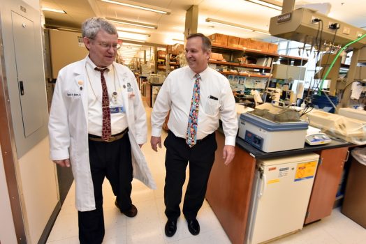 Two men walking down the hallway between research labs.