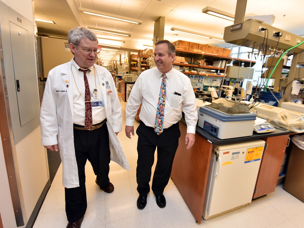 Two men walking down the hallway between research labs.