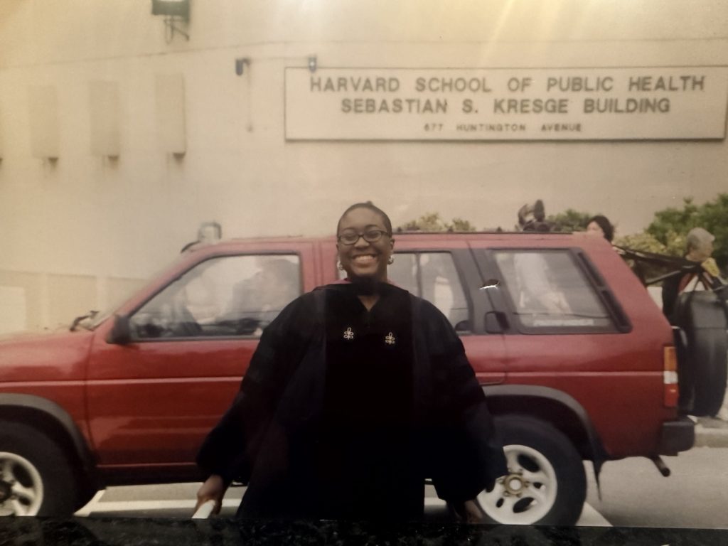 Graduate standing in front of a car.
