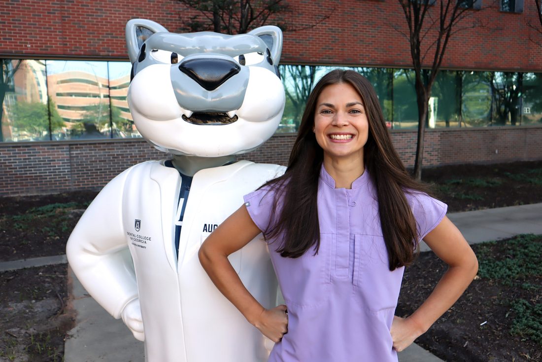 Female student smiles next to school mascot