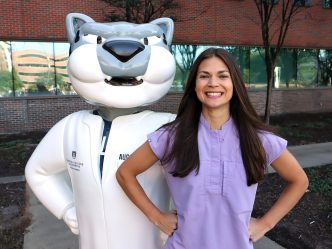 Female student smiles next to school mascot