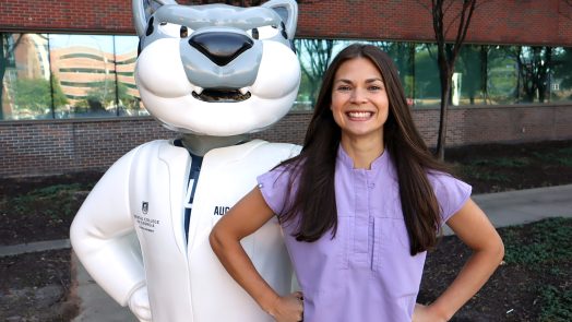 Female student smiles next to school mascot