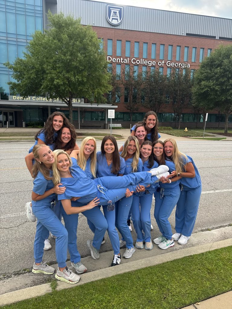 A group of women standing in front of a building posing for a photo