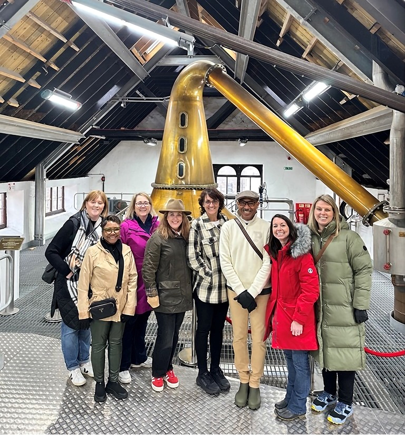 A man stands with seven women in an art gallery