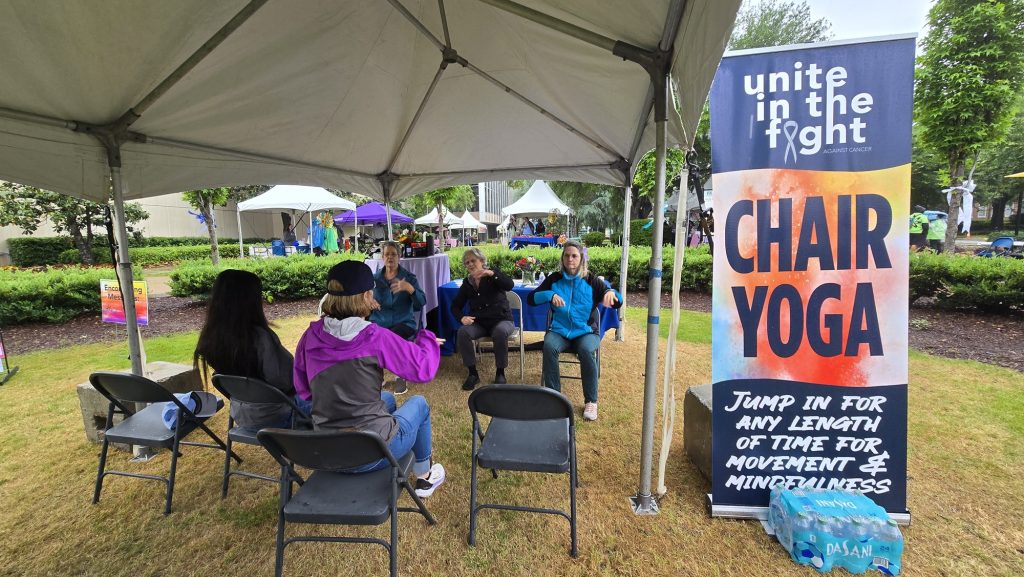 In this photo, you see people sitting in chairs and taking part in a Chair Yoga session.