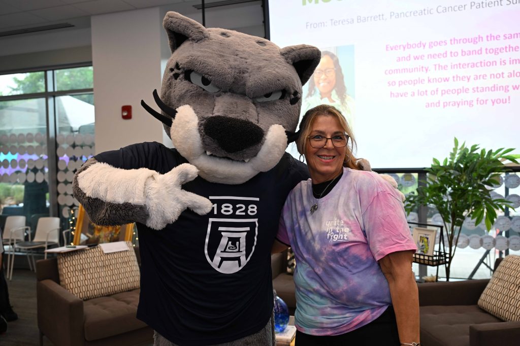 In this photo, you see a woman posing for a photo with Augustus, Augusta University's Jaguar masscot.