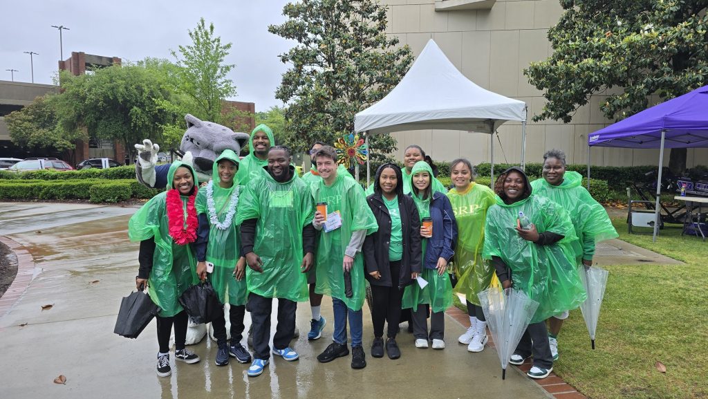 In this photo, you see people wearing green-colored ponchos standing and posing for the picture.