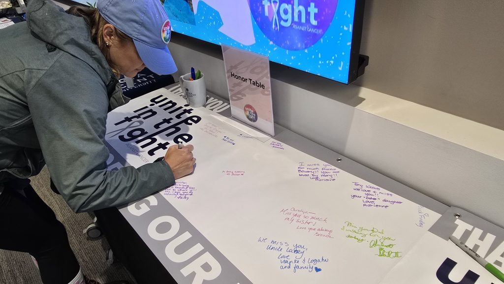 In this photo, you see a female signing a giant white banner.