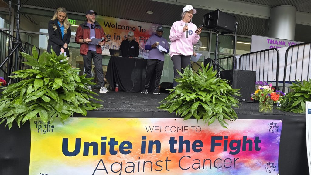 In this photo, you see a female cancer survivor speaking on a raised stage.