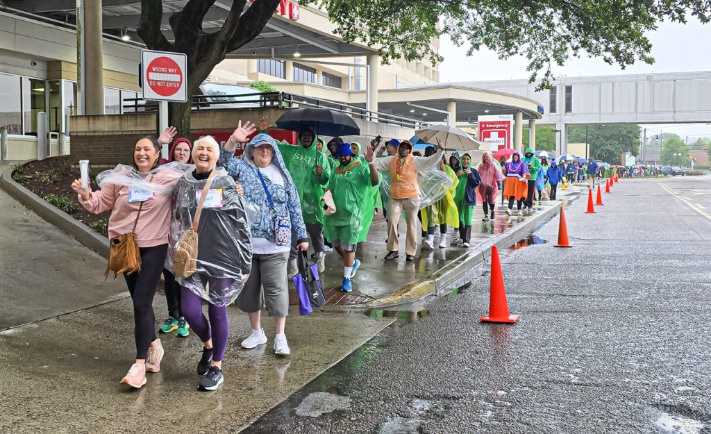 In this photo, you see people walking down a street. The people are participants in the Georgia Cancer Center's Unite in the Fight Against Cancer 2026 community event.
