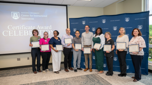 Group of men and women standing together and holding certificates.