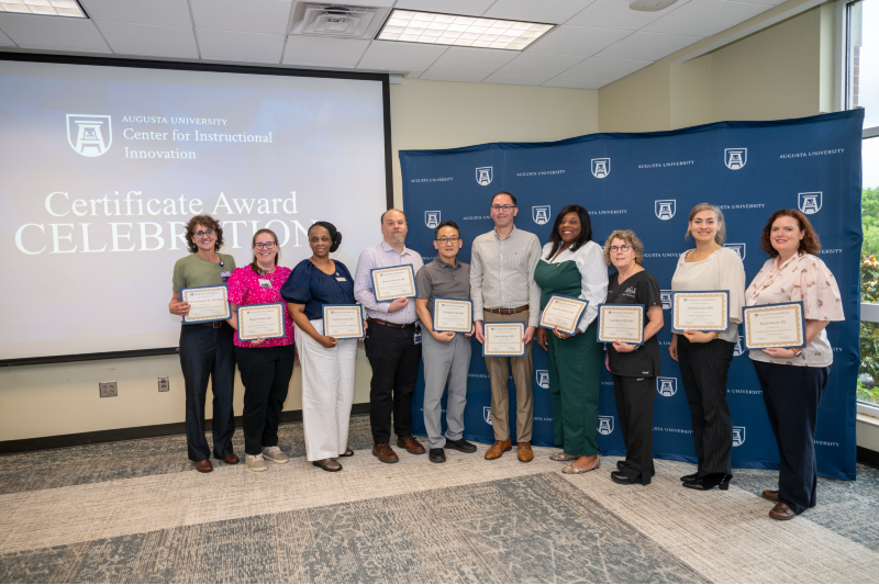 Group of men and women standing together and holding certificates.