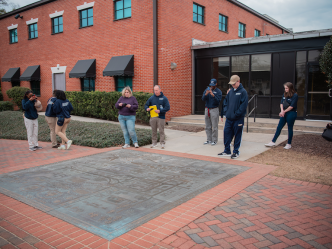 Eight people gathered around a medal mural on the ground