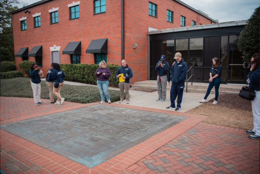 Eight people gathered around a medal mural on the ground