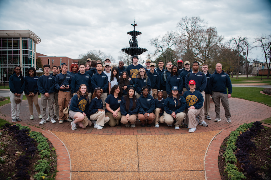 A group of high school students posed for a group photo in front of a fountain.