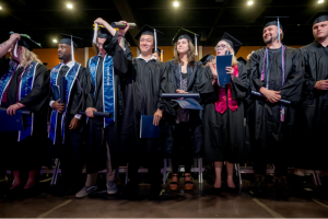 male and female students in graduation cap and gowns standing together