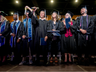 male and female students in graduation cap and gowns standing together