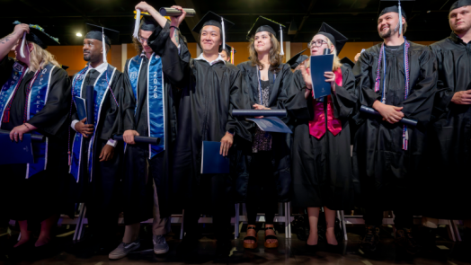 male and female students in graduation cap and gowns standing together