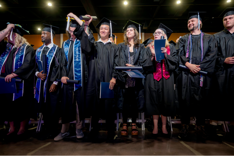 male and female students in graduation cap and gowns standing together