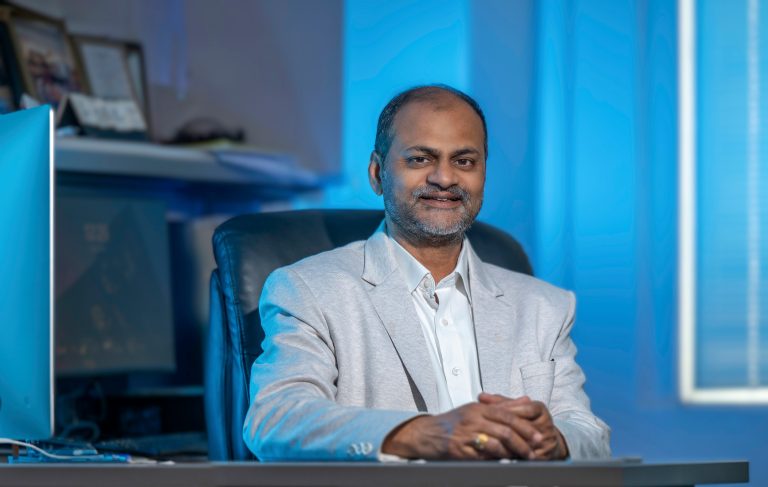 Man sitting in a suit at a desk.