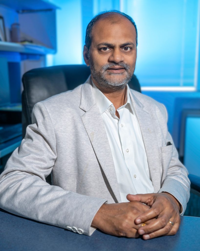 man in business dress sits with folded hands