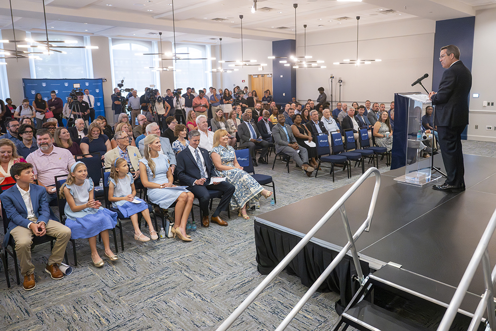 A man standing behind a podium talking to a crowd of men, women and children