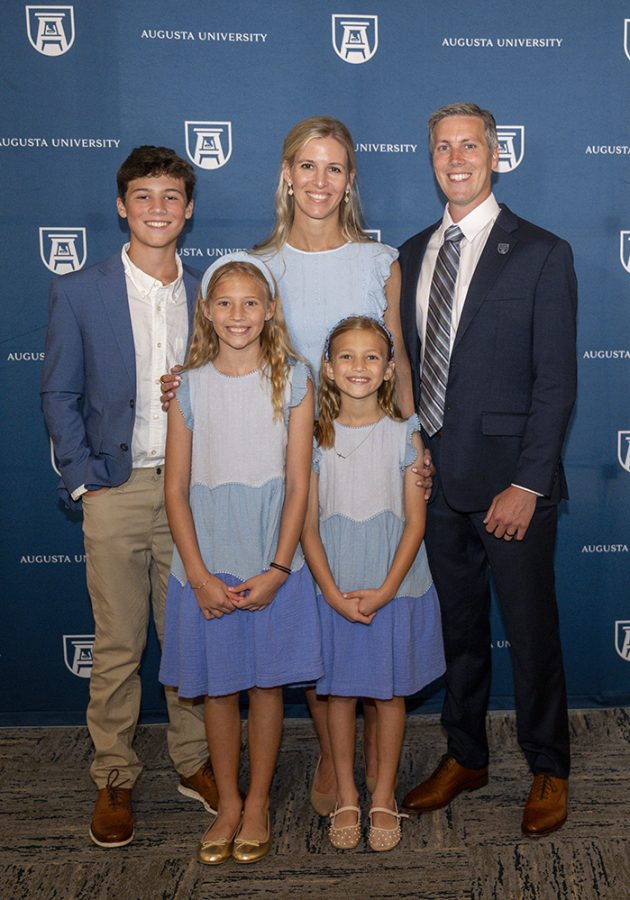 A man and a woman stand for a photo with their son and two daughters