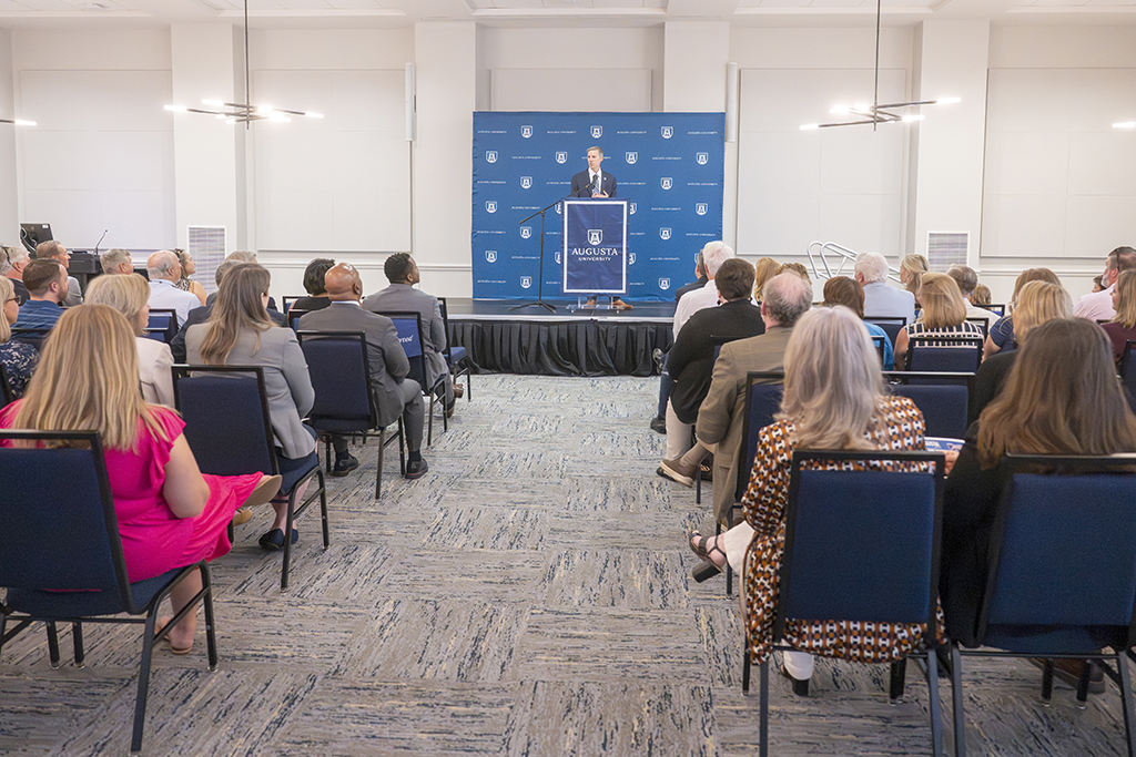 A man standing behind a podium talking to a crowd of people