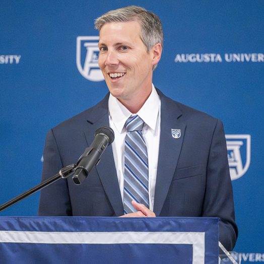 A man in a suit smiling and talking