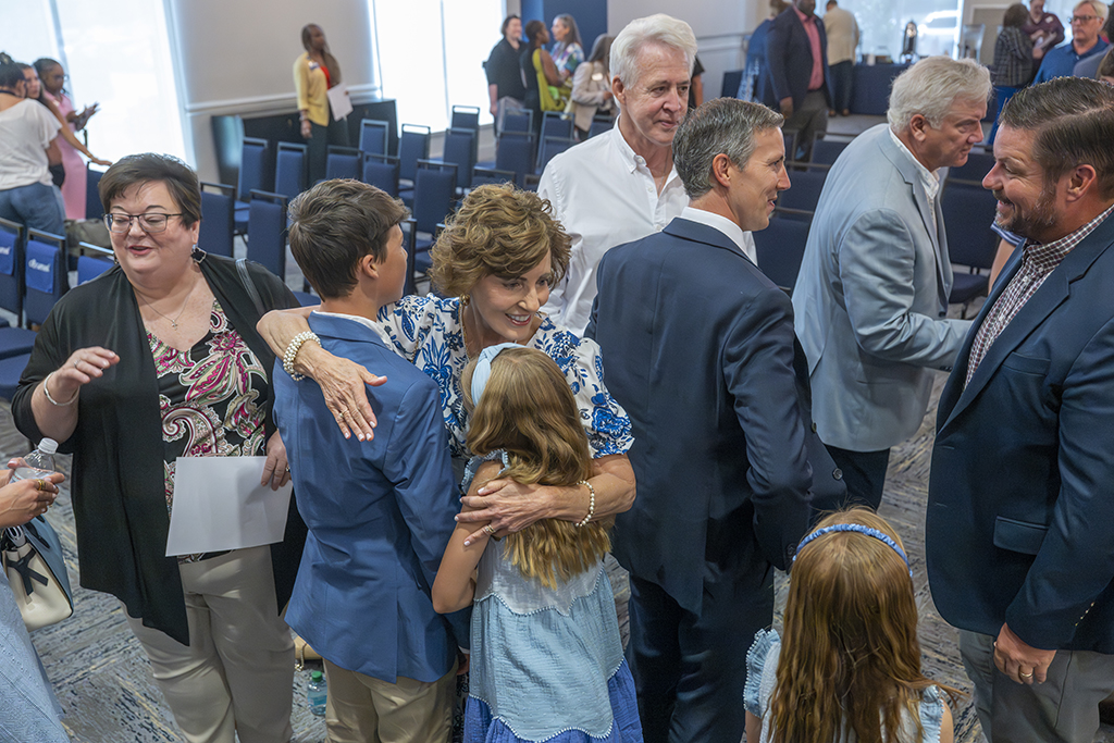 A woman hugs two children as men talk behind her