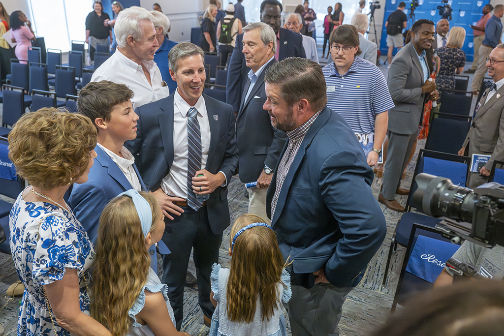 A man talks to a boy as a man and two girls look on