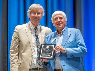 Two men in business dress, one holding a plaque.
