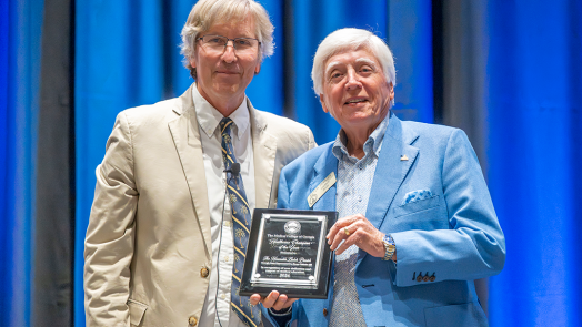 Two men in business dress, one holding a plaque.