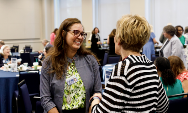 Two women smile speaking to one another