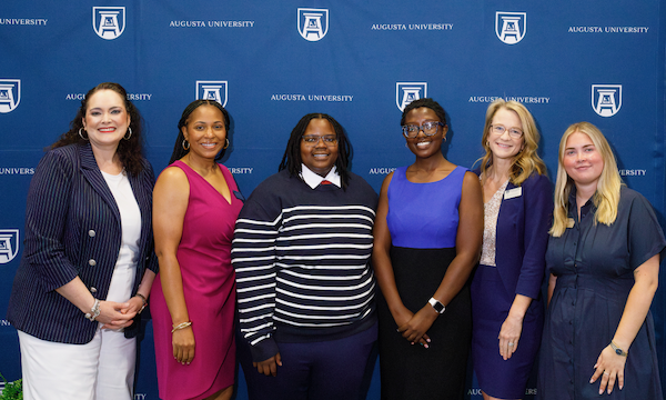 Six women stand smiling