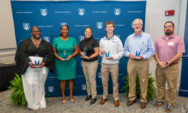 3 men and 3 women stand smiling holding awards