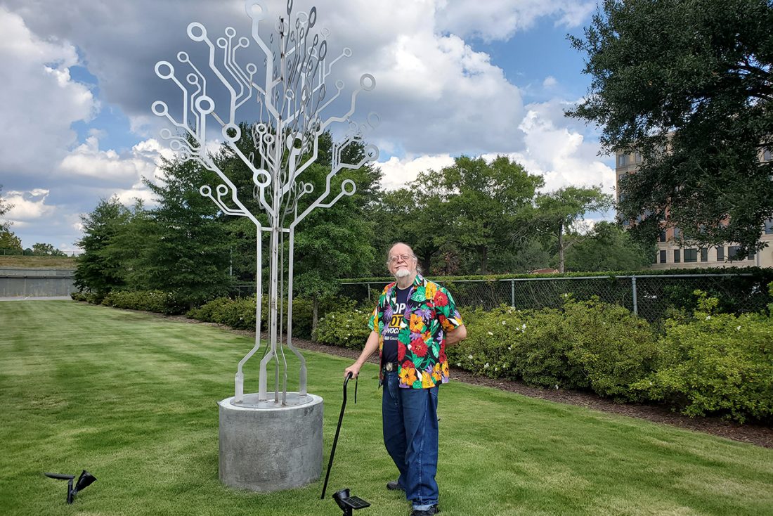 Man standing next to metal sculpture