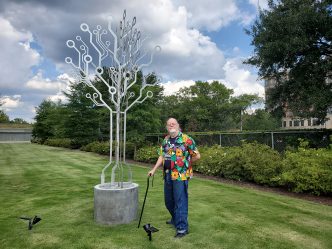 Man standing next to metal sculpture