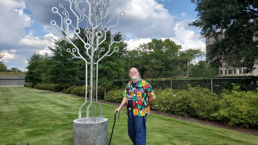 Man standing next to metal sculpture