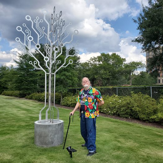 Man standing next to metal sculpture