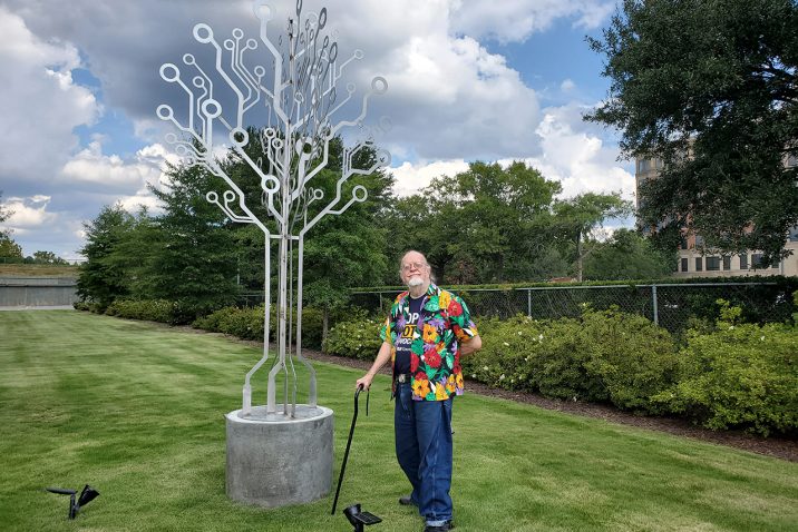 Man standing next to metal sculpture