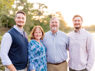 Three men and one woman stand together posing for a photo