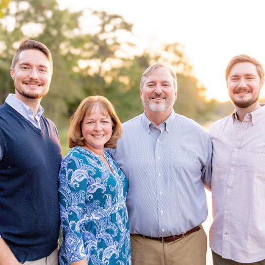 Three men and one woman stand together posing for a photo