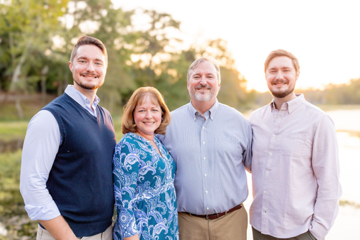Three men and one woman stand together posing for a photo
