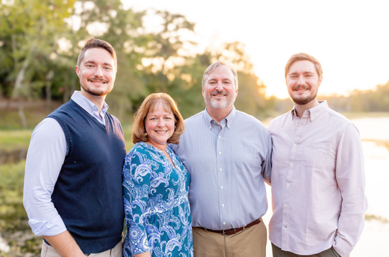Three men and one woman stand together posing for a photo