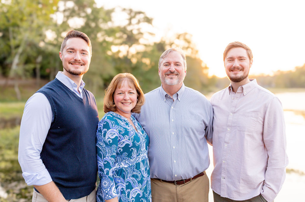 Three men and one woman stand together posing for a photo