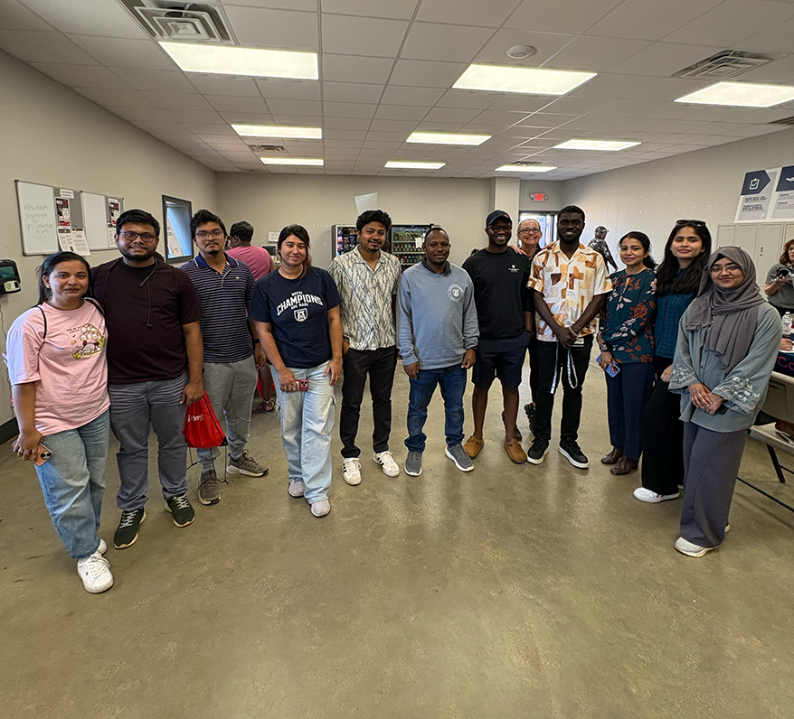 A group of PhD and master's students standing together at a health fair smiling at the camera.